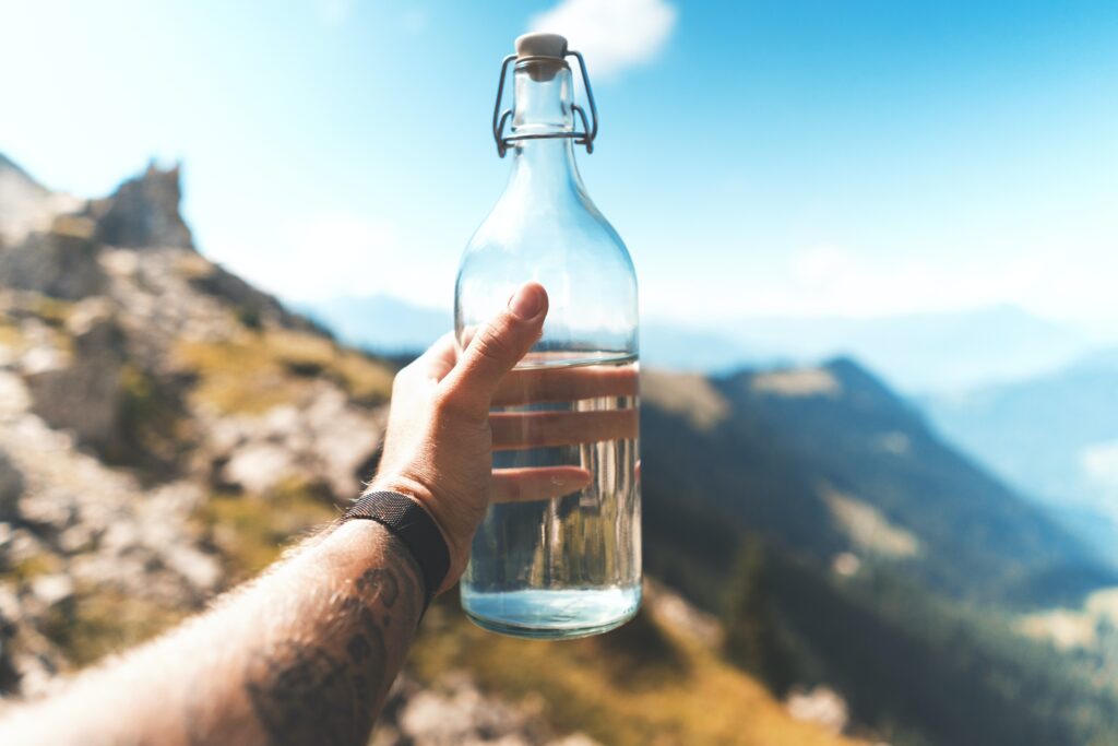 Flasche mit Trinkwasser vor einem Alpenpanorama